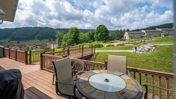 Eine Terrasse mit Gartenmöbeln und einem schönen Blick auf eine grüne Landschaft und Gebäude.