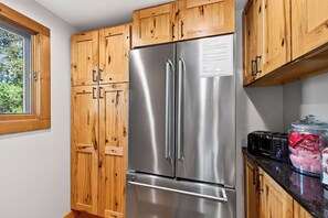 A kitchen with wooden cabinets, a stainless steel refrigerator, a toaster, and a jar of food. - Updated townhome - Walk to Holiday Valley (Ellicottville)