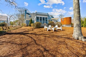 A house with a covered patio area, a fenced yard, and a tree.