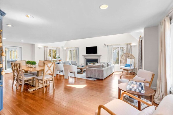 A spacious living room with a fireplace, a dining area with wooden furniture, and a seating area with a round table.