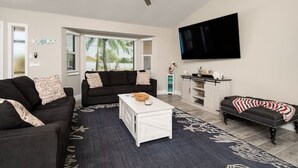 A living room with a black sofa, a white coffee table, and a patterned rug.