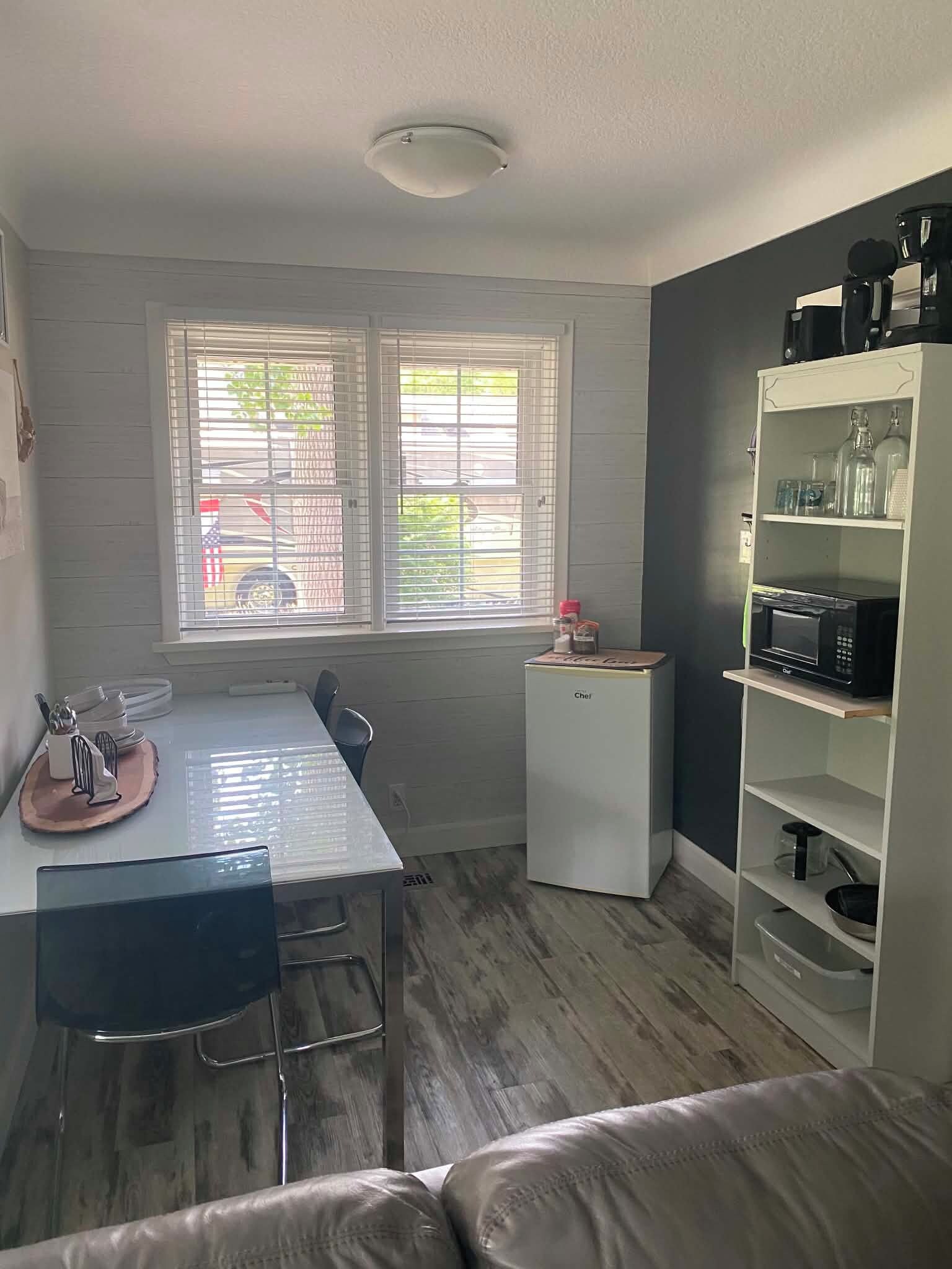 A compact kitchen with a dining table, a microwave, and a small refrigerator.
