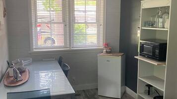 A compact kitchen with a dining table, a microwave, and a small refrigerator.