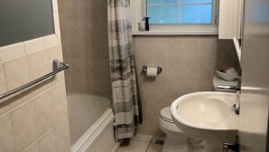 Une petite salle de bain avec une douche, des toilettes, un lavabo et une fenêtre.