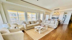A spacious living room with a large sectional sofa, a coffee table, and a dining area with a chandelier.