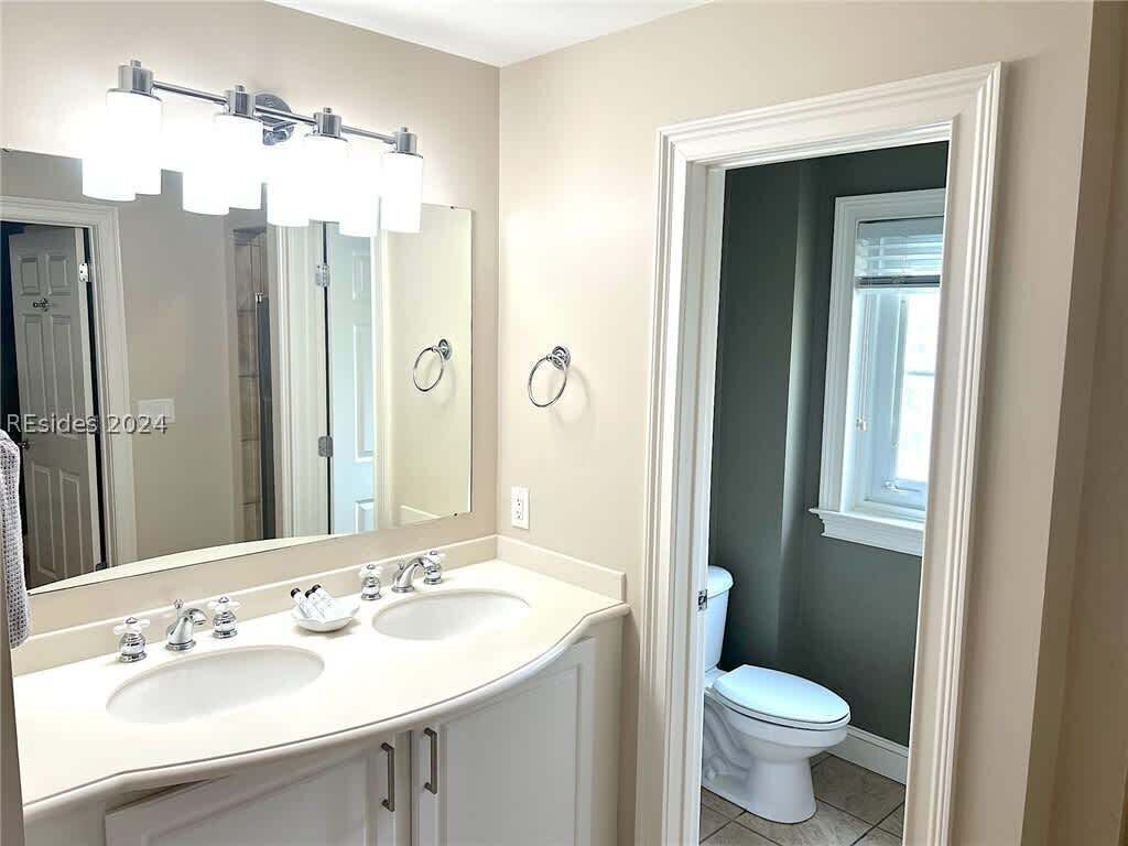 A bathroom with two sinks, a large mirror, and a toilet.