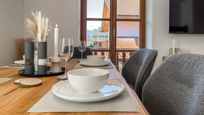 Un coin repas avec une table en bois mise pour deux personnes, agrémentée d’un bol blanc et de verres à vin.