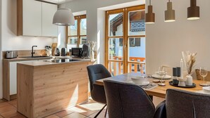 Une cuisine moderne avec des meubles en bois, un îlot central et un coin repas avec une table dressée pour deux personnes.