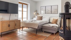Une chambre à coucher avec un lit, un canapé, une télévision, une cheminée et des œuvres d’art accrochées au mur.