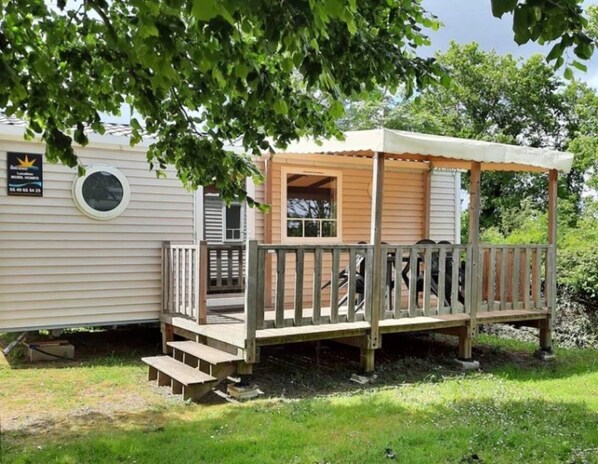 A mobile home with a wooden deck and a covered porch.