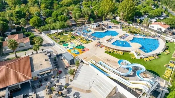 A resort with multiple swimming pools, a water slide, and a large grassy area.