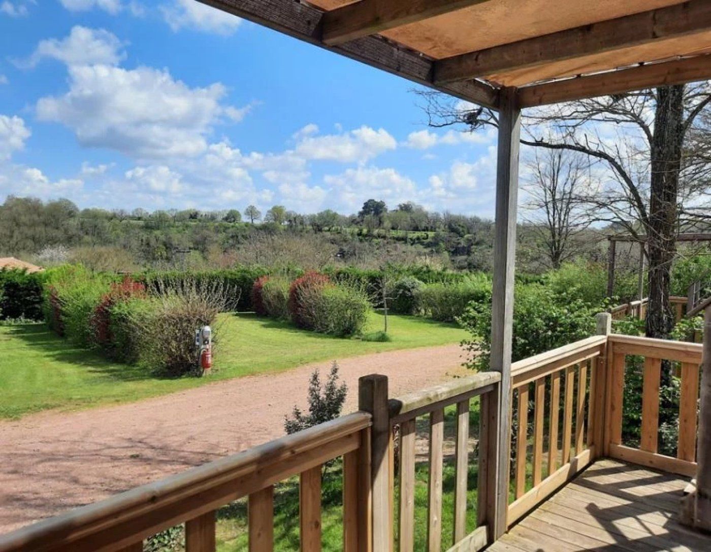 A wooden deck with a view of a landscaped garden and a dirt path.