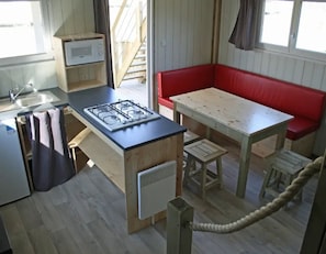 Una cocina compacta con estufa a gas, lavamanos y armarios de madera.