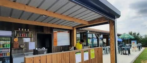 A wooden structure with a metal roof, a counter, and a person standing inside.