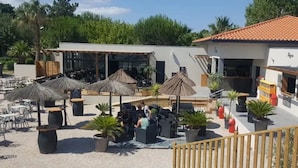 Un espacio al aire libre con mesas, sillas, sombrillas y plantas en macetas.
