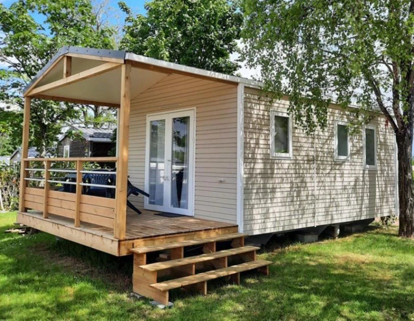 A mobile home with a covered porch, a sliding door, and a small deck.
