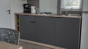 Cocina compacta con microondas, cafetera y cocina a gas.