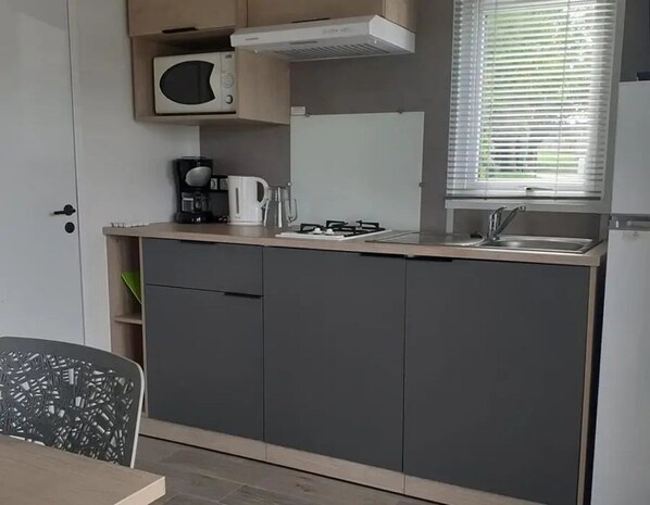 Cocina compacta con microondas, cafetera y cocina a gas.