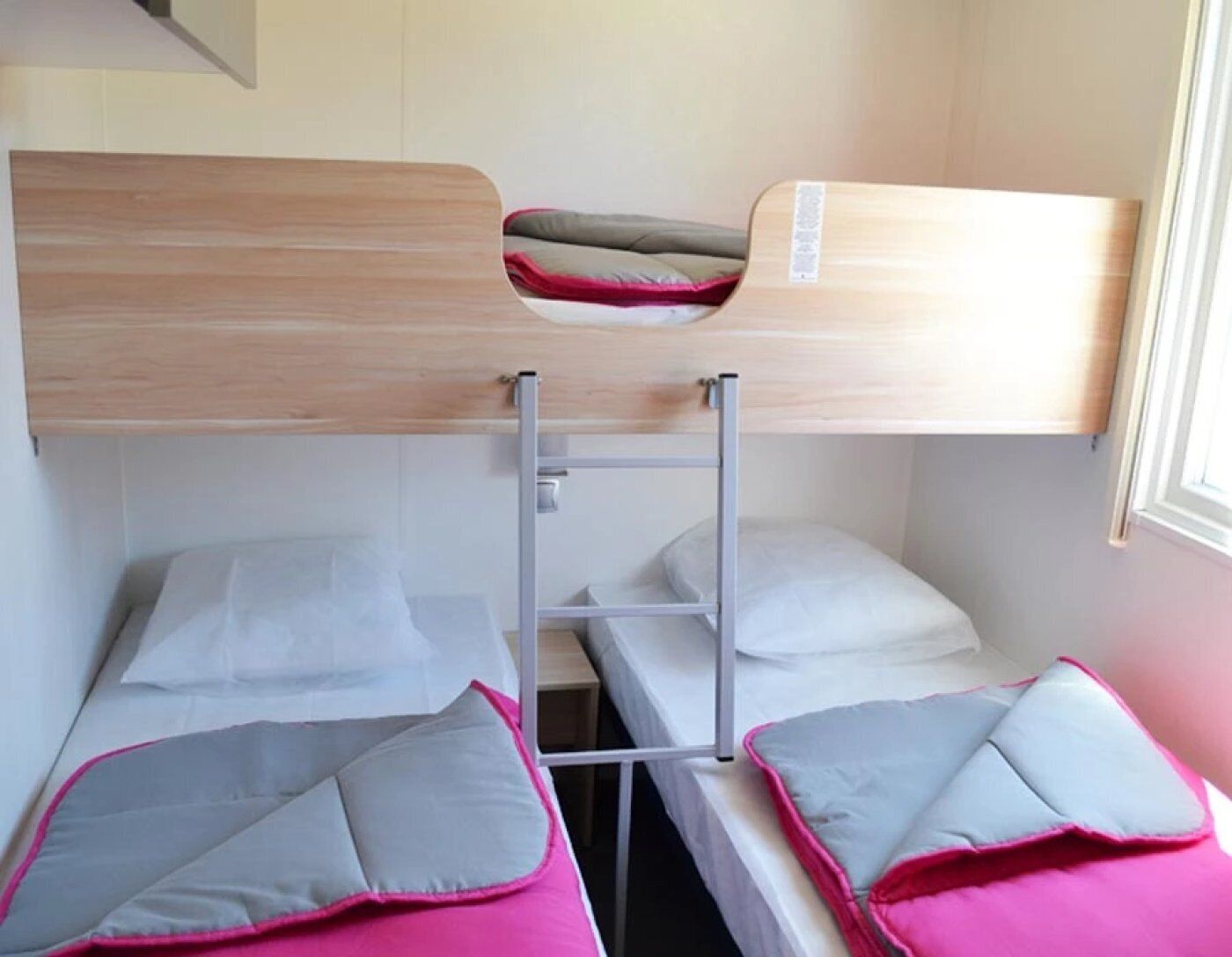 A bunk bed room with a ladder, two beds, and a window.