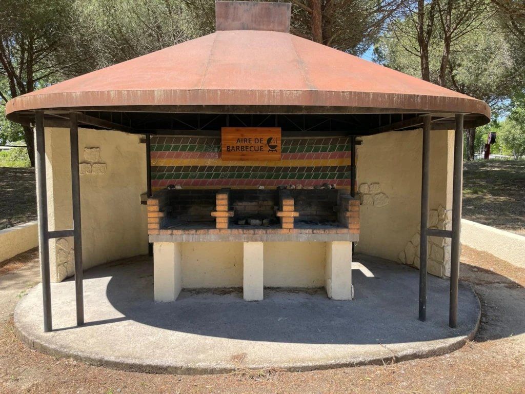 A barbecue area with a tiled wall and a sign that reads "AIRE DE BARBECUE".