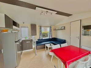 Uma cozinha compacta com área de refeições, um banco embutido e uma mesa vermelha.