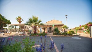Een hotel met een receptie, terras en parkeerplaats.