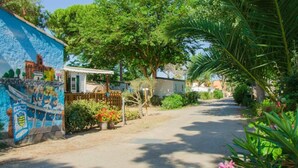 A residential street with a mural, a small house, and lush greenery. - ZEcamping 4 étoiles locatif TV LV BBQ 21m2 (Agde)