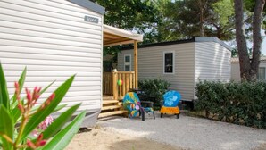 A mobile home with a porch and a small deck. There are two chairs with colorful covers. - ZEcamping 4 étoiles locatif TV LV BBQ 21m2 (Agde)