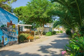 A residential street with a mural, a small house, and lush greenery.