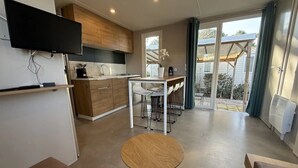 Une cuisine moderne équipée d’un téléviseur à écran plat, d’un coin repas avec une table ronde et offrant une vue sur l’extérieur grâce à de grandes portes coulissantes.