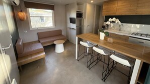 Une cuisine compacte dotée d’un plan de travail en bois, de tabourets de bar, d’un four encastré et d’un réfrigérateur.