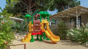 A playground with a slide, climbing structures, and a covered seating area. - ZEcamping 4* animé 1km plage piscine chauffée locatif TV LV BBQ 31m2 (Agde)