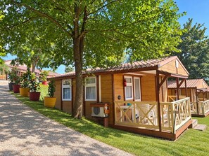 A wooden cabin with a porch, a small table, and potted plants. - ZEcamping 3* piscine chalet TV clim 24m2 5 pers (Durfort)
