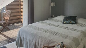 A bedroom with a bed, a chair, a window, and a painting on the wall.