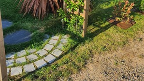 A garden with a wooden trellis, a variety of plants, and a stone pathway.