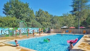 A swimming pool with people, inflatable toys, and a mural.