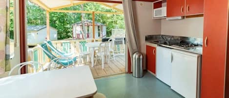 Una cocina compacta con comedor, un refrigerador pequeño y un microondas.