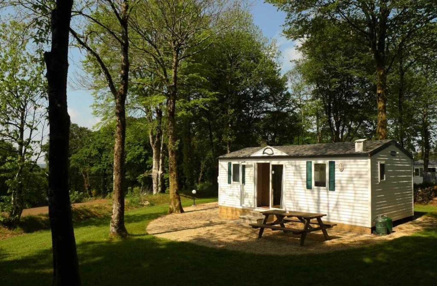 A small cabin with a picnic table in a wooded area.