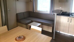 Et kompakt tekøkken med et indbygget komfur, et lille spisebord og en bænk med opbevaring under.