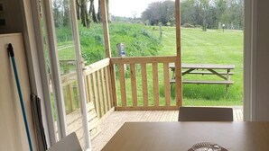 Et værelse med et træbord, en bænk og udsigt til et græsområde med et picnicbord udenfor.