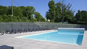 Une piscine avec des chaises longues et un espace abrité.