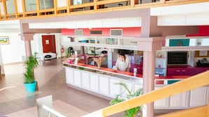 Zona d'arribada d'un hotel amb un mostrador, un recepcionista i una escala que condueix a una planta superior.