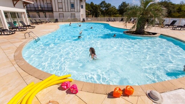 Una piscina amb gandules i un edifici al fons.