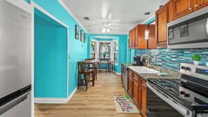Une cuisine aux murs de couleur turquoise, avec des meubles en bois et une cuisinière moderne en acier inoxydable.
