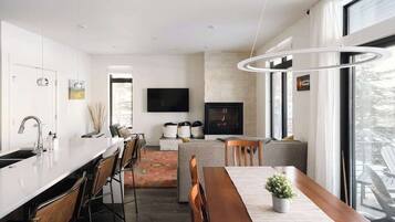 A modern kitchen with a central island, a dining area with a wooden table, and a fireplace.
