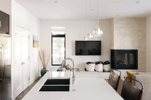 A modern kitchen with a large island, a built-in TV, and a fireplace.