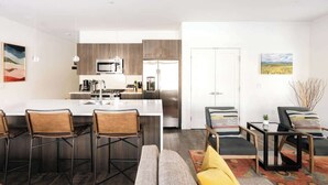 Une cuisine moderne dotée d’un îlot central, de tabourets de bar et d’un coin salon avec un canapé et des fauteuils.
