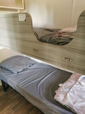 Una cama individual con cabecera, mesita de noche y un pequeño cajón.