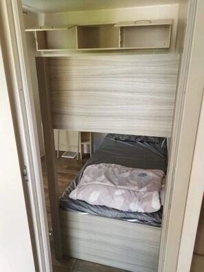 Ein kleines Zimmer mit Etagenbett, Schreibtisch und Ablagefläche.