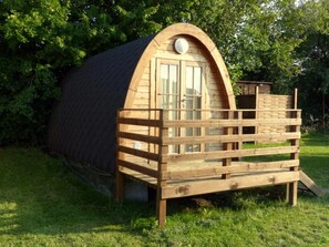 Una estructura de madera con techo inclinado, una puerta y un pequeño porche.
